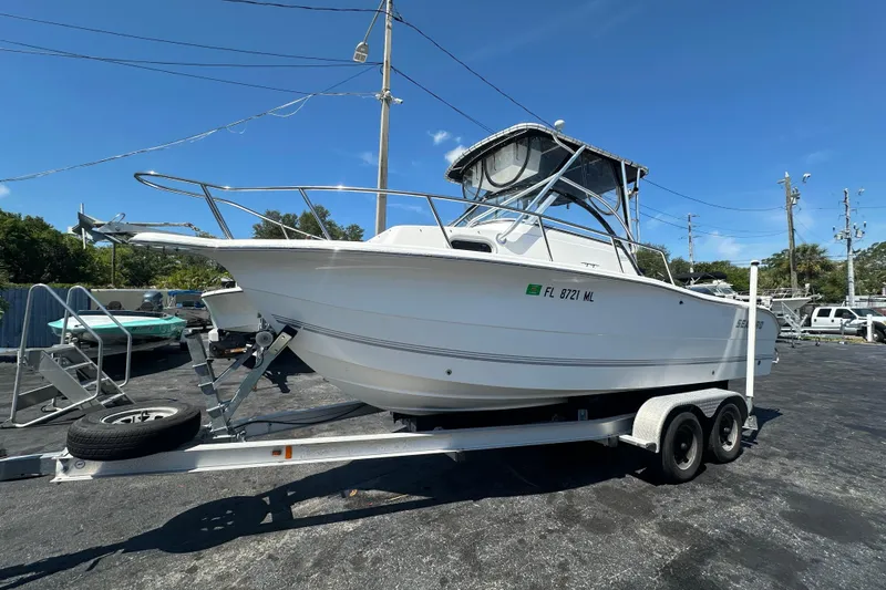 Slide: The Image of 2004 Sea Pro 220 Walk Around boat on trailer, parked outdoors under clear blue sky. - 8
