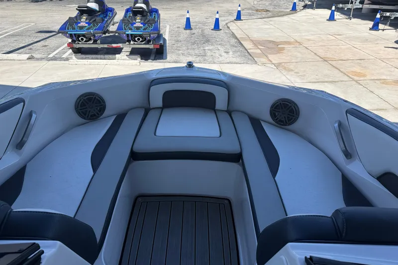 Slide: The Image of 2023 Yamaha Boats 195S interior with seating and speakers, parked near jet skis. - 16