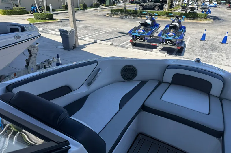 Slide: The Image of 2023 Yamaha Boats 195S interior with sleek seating, parked near jet skis. - 17