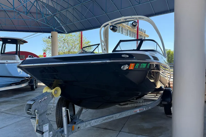 Slide: The Image of 2023 Yamaha Boats 195S on trailer under canopy, sleek black design. - 4