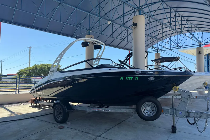 Slide: The Image of 2023 Yamaha Boats 195S on trailer under canopy, side view. - 6