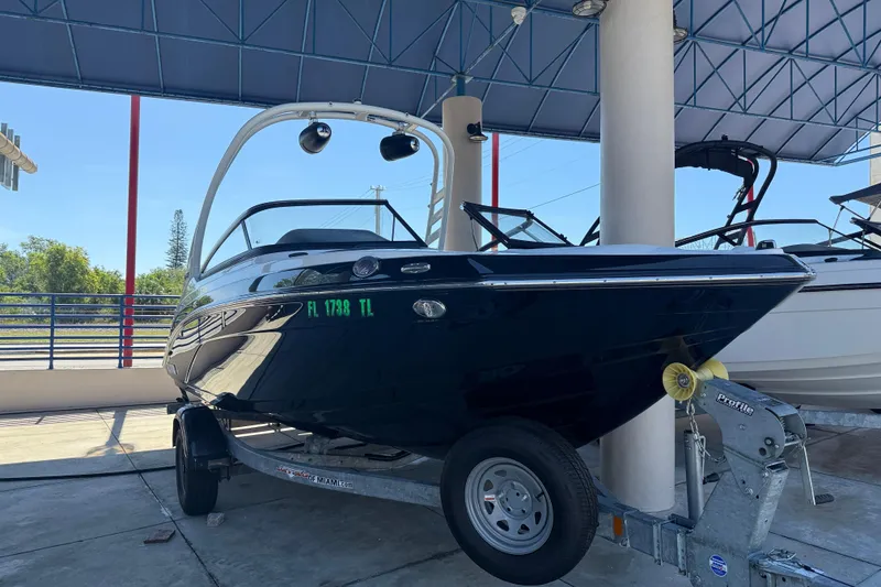 Slide: The Image of 2023 Yamaha Boats 195S on trailer under canopy, side view. - 9