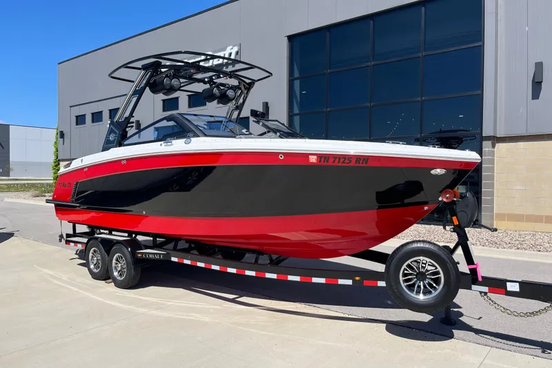 The Image of 2023 Cobalt R8 Surf boat in black and red on a trailer outside a building. - 1