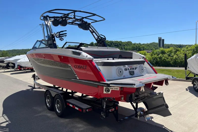 Slide: The Image of 2023 Cobalt R8 Surf boat on trailer, red and gray design, parked outdoors. - 5