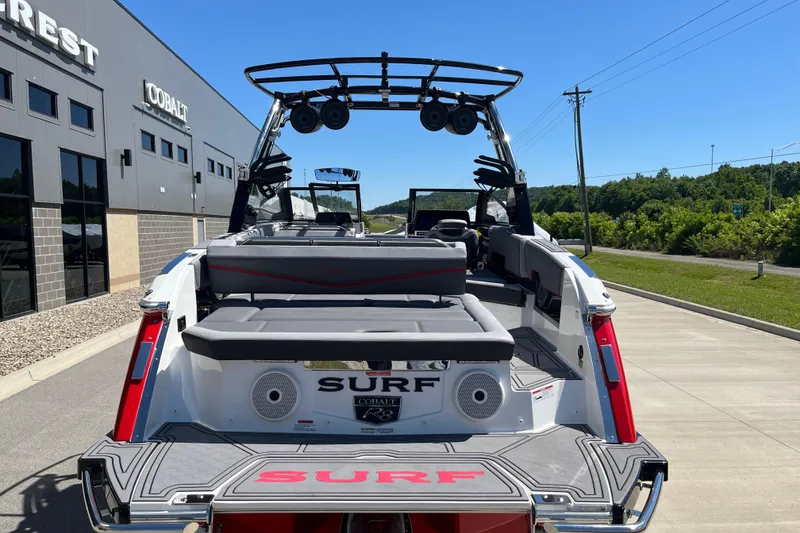 Slide: The Image of 2023 Cobalt R8 Surf boat, rear view, parked outside dealership on a sunny day. - 7