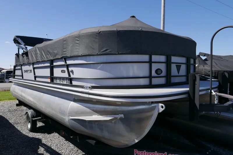 Slide: The Image of 2023 Trifecta C Series pontoon boat with cover, parked on a trailer. - 14