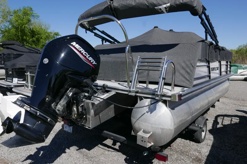 Slide: The Image of 2023 Trifecta C Series pontoon boat with Mercury outboard motor, parked on gravel. - 16
