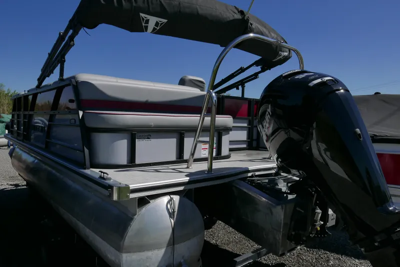 Slide: The Image of 2023 Trifecta C Series pontoon boat with Mercury outboard motor, docked on gravel. - 4