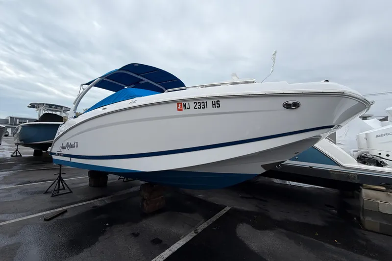 Slide: The Image of 2023 Four Winns HD5 OB boat with blue canopy, parked on a cloudy day. - 2