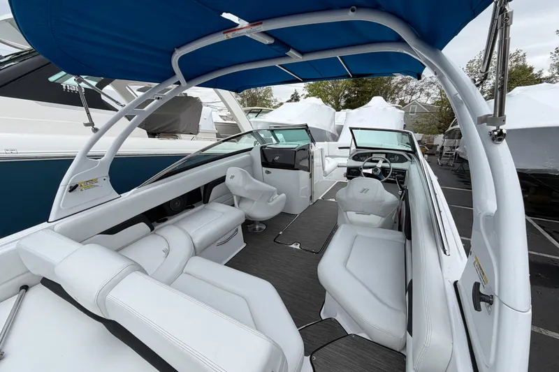 Slide: The Image of 2023 Four Winns HD5 OB boat with white seating and outboard motor in a marina. - 34