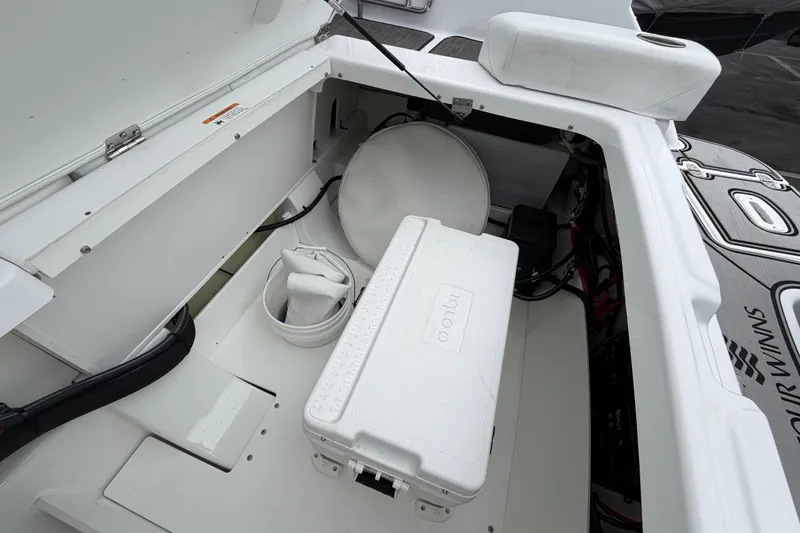 Slide: The Image of 2023 Four Winns HD5 OB boat with sleek white seating and outboard motor in a marina. - 40