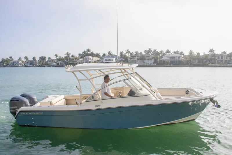 The Image of 2020 Grady-White Freedom 285 boat cruising on calm waters near waterfront homes. - 1