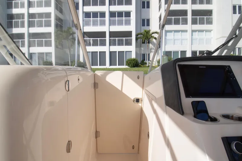 Slide: The Image of 2020 Grady-White Freedom 285 boat interior with modern dashboard, near waterfront buildings. - 13