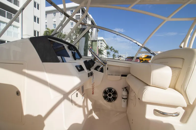 Slide: The Image of 2020 Grady-White Freedom 285 boat interior with helm and seating, docked near buildings. - 18