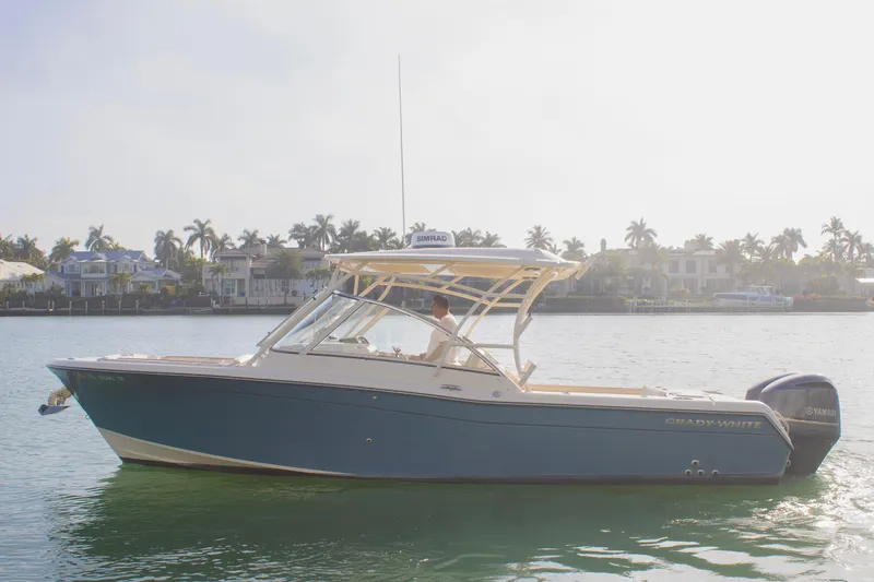 Slide: The Image of 2020 Grady-White Freedom 285 boat on calm water, with coastal homes in the background. - 5