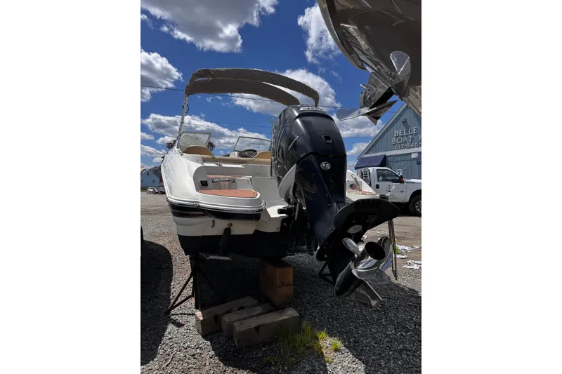 The Image of 2015 Stingray 234 LR boat with outboard motor on display under a blue sky. - 1