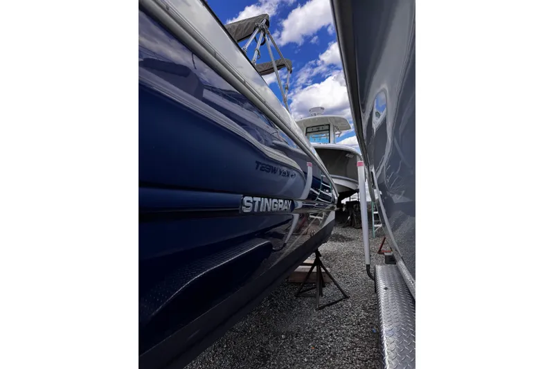 Slide: The Image of 2015 Stingray 234 LR boat in storage, side view with blue hull and clear sky. - 11