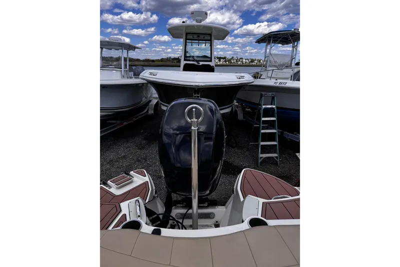 Slide: The Image of 2015 Stingray 234 LR boat with outboard motor, docked under cloudy sky. - 13