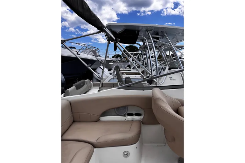 Slide: The Image of 2015 Stingray 234 LR boat interior with beige seating and metal framework under a blue sky. - 15