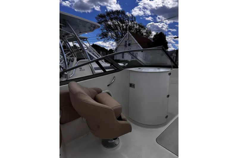 Slide: The Image of 2015 Stingray 234 LR boat interior with tan seating and console under a cloudy sky. - 18