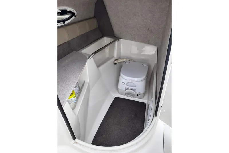 Slide: The Image of Interior of a 2015 Stingray 234 LR boat featuring a compact marine toilet. - 21