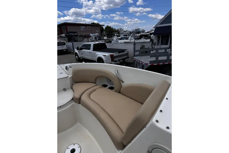 Slide: The Image of 2015 Stingray 234 LR boat with beige seating, parked outdoors under a cloudy sky. - 28