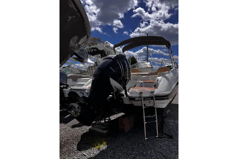 Slide: The Image of 2015 Stingray 234 LR boat with Mercury outboard motor, parked under a cloudy sky. - 3