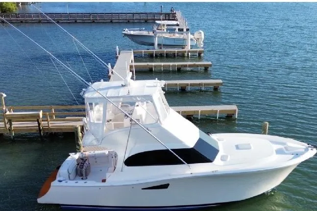 The Image of 2008 Luhrs 36 Convertible yacht docked on calm water, showcasing sleek design and fishing equipment. - 0