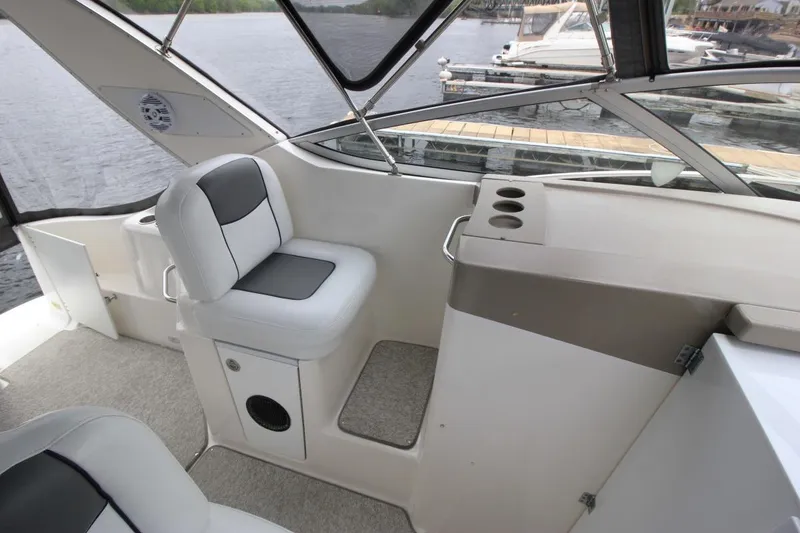 Slide: The Image of 2001 Bayliner 3055 Ciera cockpit with seating and cup holders, docked by the water. - 11