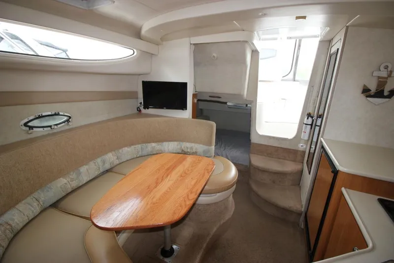 Slide: The Image of 2001 Bayliner 3055 Ciera interior with cozy seating, wooden table, and compact kitchenette. - 16