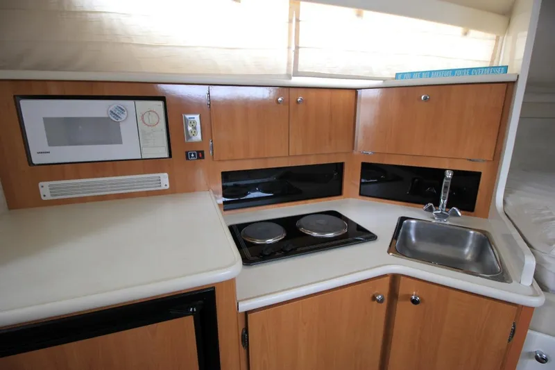 Slide: The Image of 2001 Bayliner 3055 Ciera kitchen with microwave, stove, sink, and wooden cabinets. - 20