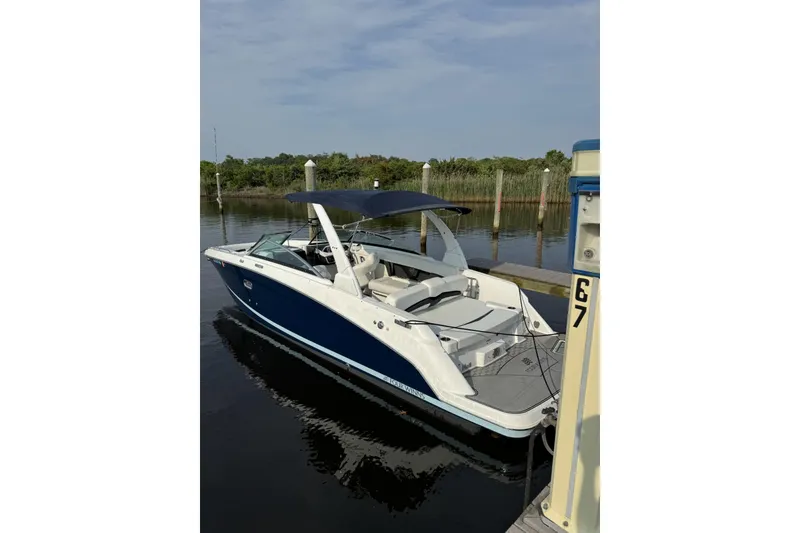 Slide: The Image of 2023 Four Winns HD8 boat docked, featuring sleek design and blue hull. - 2