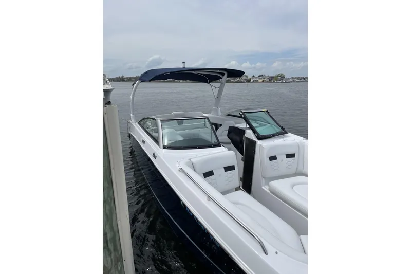 Slide: The Image of 2023 Four Winns HD8 boat docked on calm water, featuring sleek design and spacious seating. - 3