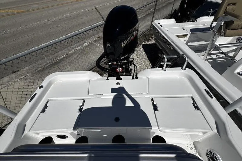 Slide: The Image of 2026 Blazer Bay 2200 boat with outboard motor, docked near a fence. - 21