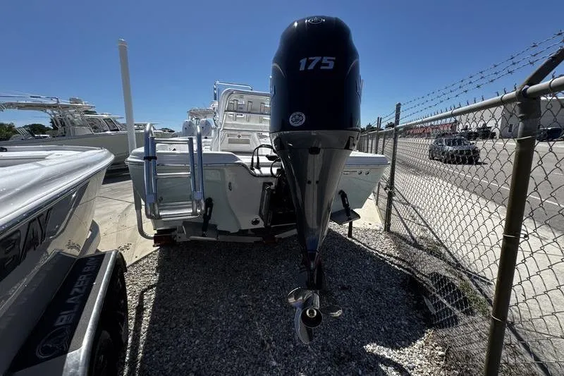 Slide: The Image of 2026 Blazer Bay 2200 boat with 175 horsepower engine, parked near a fence. - 3
