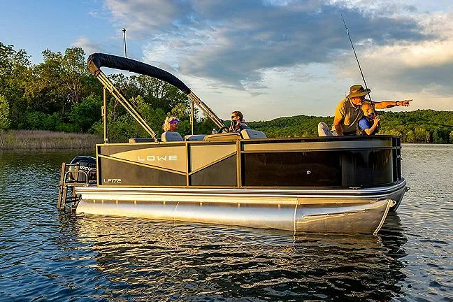 Slide: The Image of Manufacturer Provided Image: 2025 Lowe LF 172 pontoon boat on a serene lake with people fishing. - 2