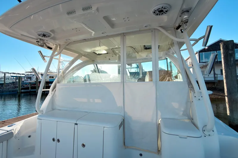 Slide: The Image of 2021 Pursuit OS 385 Offshore boat interior with white seating and storage, docked at marina. - 11