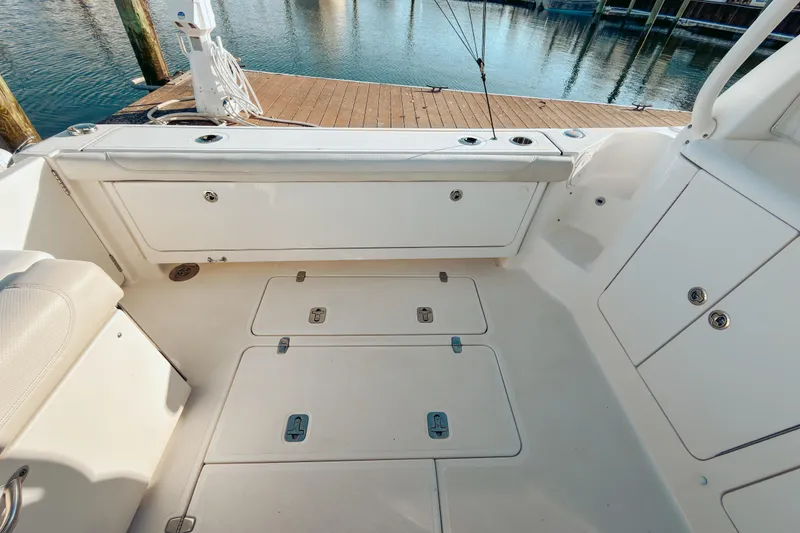 Slide: The Image of 2021 Pursuit OS 385 Offshore boat deck with storage compartments, docked by the water. - 13