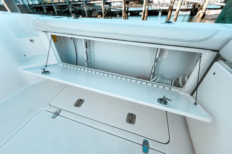 Slide: The Image of 2021 Pursuit OS 385 Offshore boat storage compartment with open hatch, dockside view. - 17