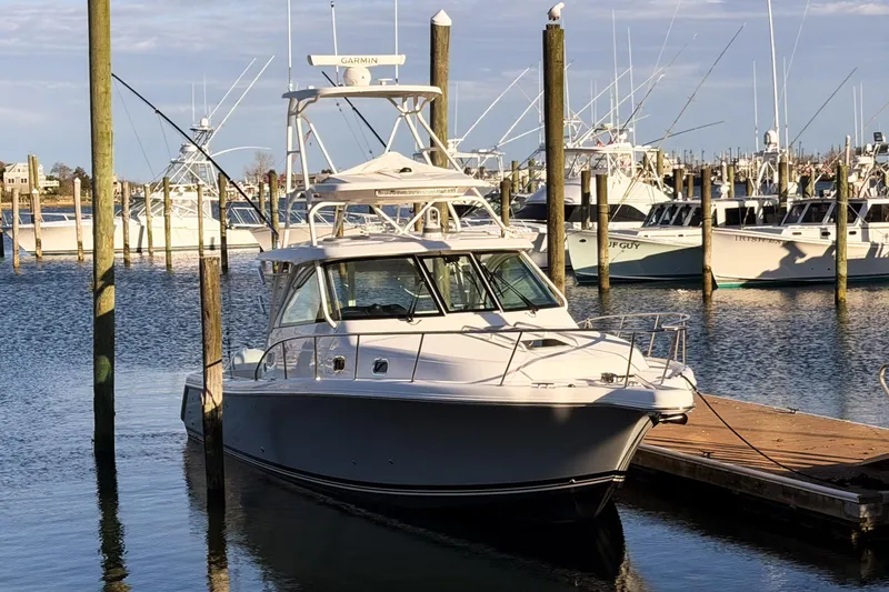 Slide: The Image of 2021 Pursuit OS 385 Offshore boat docked in a marina under clear skies. - 2