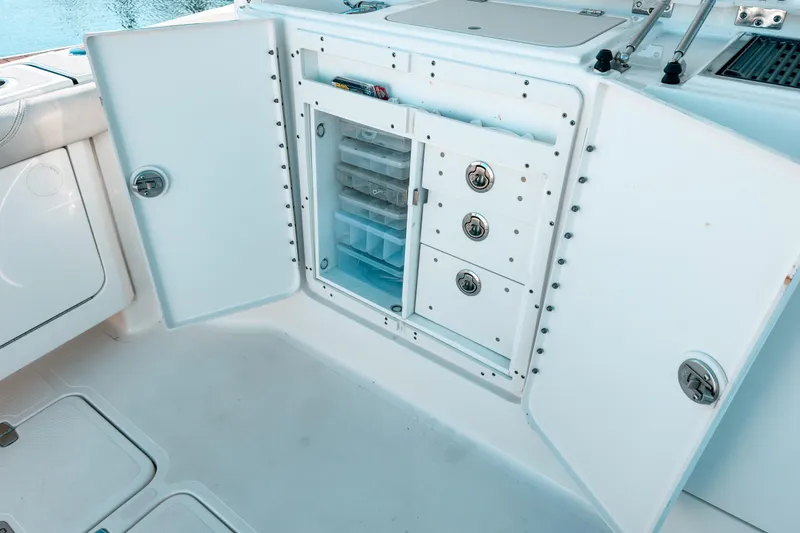 Slide: The Image of Open storage compartment on 2021 Pursuit OS 385 Offshore boat, featuring organized drawers and shelves. - 25