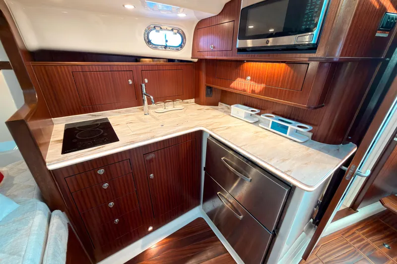Slide: The Image of Luxurious 2021 Pursuit OS 385 Offshore yacht kitchen with wood cabinetry and modern appliances. - 44