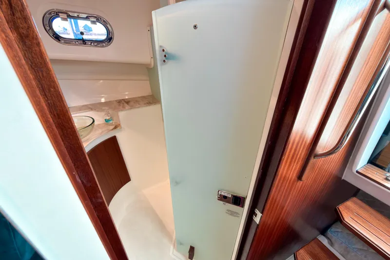 Slide: The Image of 2021 Pursuit OS 385 Offshore yacht bathroom interior with wooden accents and porthole window. - 53