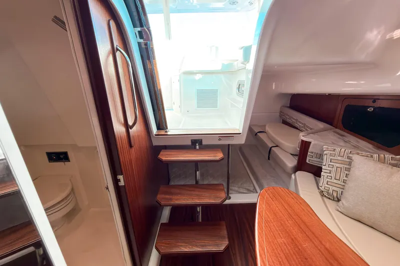 Slide: The Image of Interior of 2021 Pursuit OS 385 Offshore boat with wooden stairs and seating area. - 54