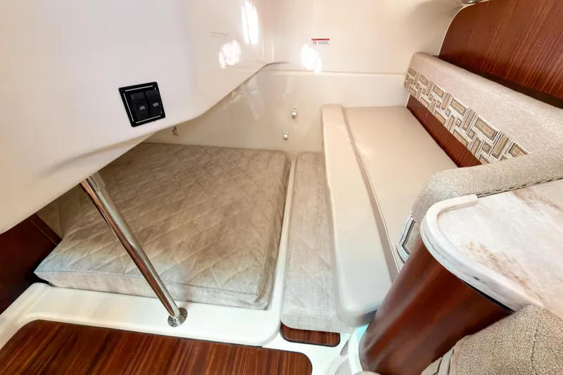 Slide: The Image of 2021 Pursuit OS 385 Offshore cabin interior with cushioned seating and wooden accents. - 55