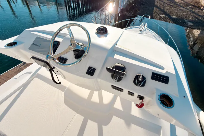 Slide: The Image of 2021 Pursuit OS 385 Offshore helm with steering wheel and controls, docked by water. - 58