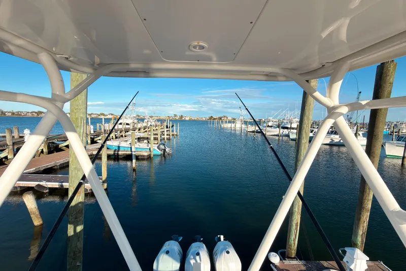 Slide: The Image of 2021 Pursuit OS 385 Offshore boat docked at a marina with fishing rods. - 65