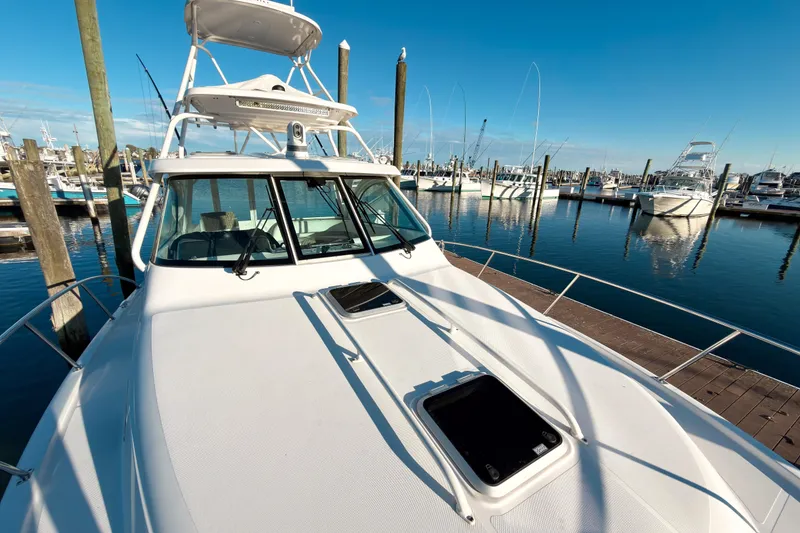 Slide: The Image of 2021 Pursuit OS 385 Offshore boat docked at a marina under clear blue skies. - 71