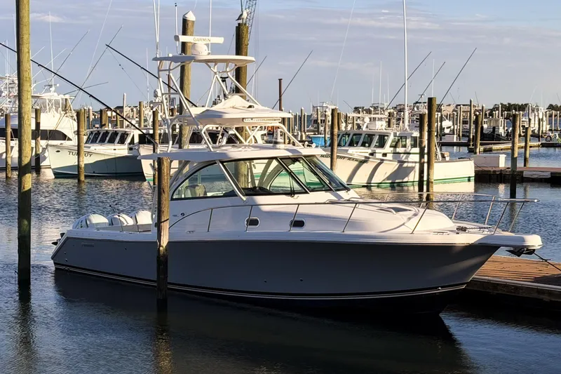 Slide: The Image of 2021 Pursuit OS 385 Offshore boat docked at a marina with other vessels. - 75