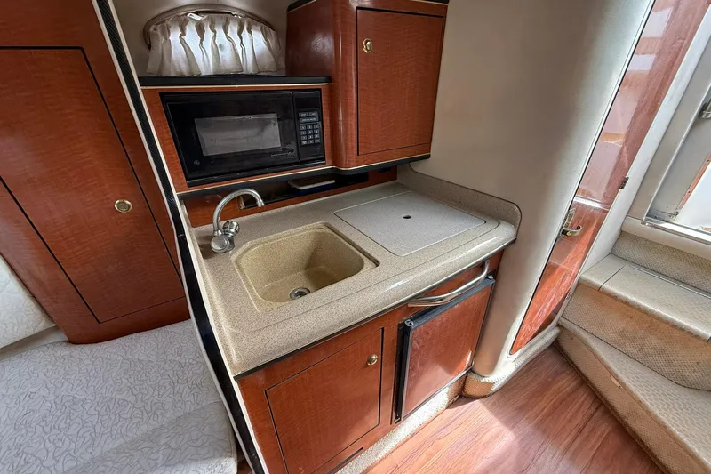 Slide: The Image of 2001 Sea Ray 280 Sundancer interior kitchen with sink, microwave, and wood cabinetry. - 13
